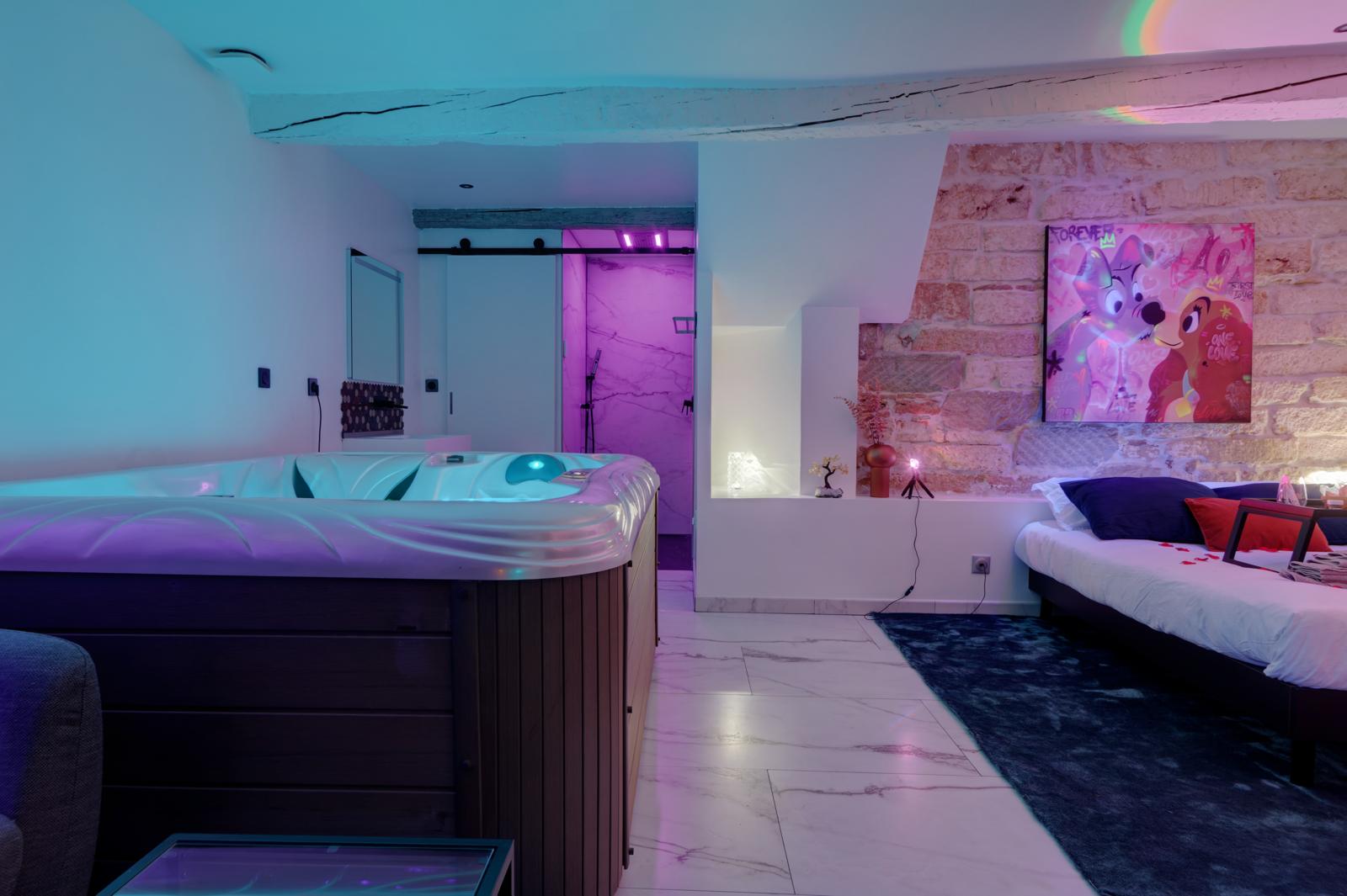 Suite avec jacuzzi privatif, mur en pierres apparentes et éclairage d'ambiance LED — réalisation AMELA Concept